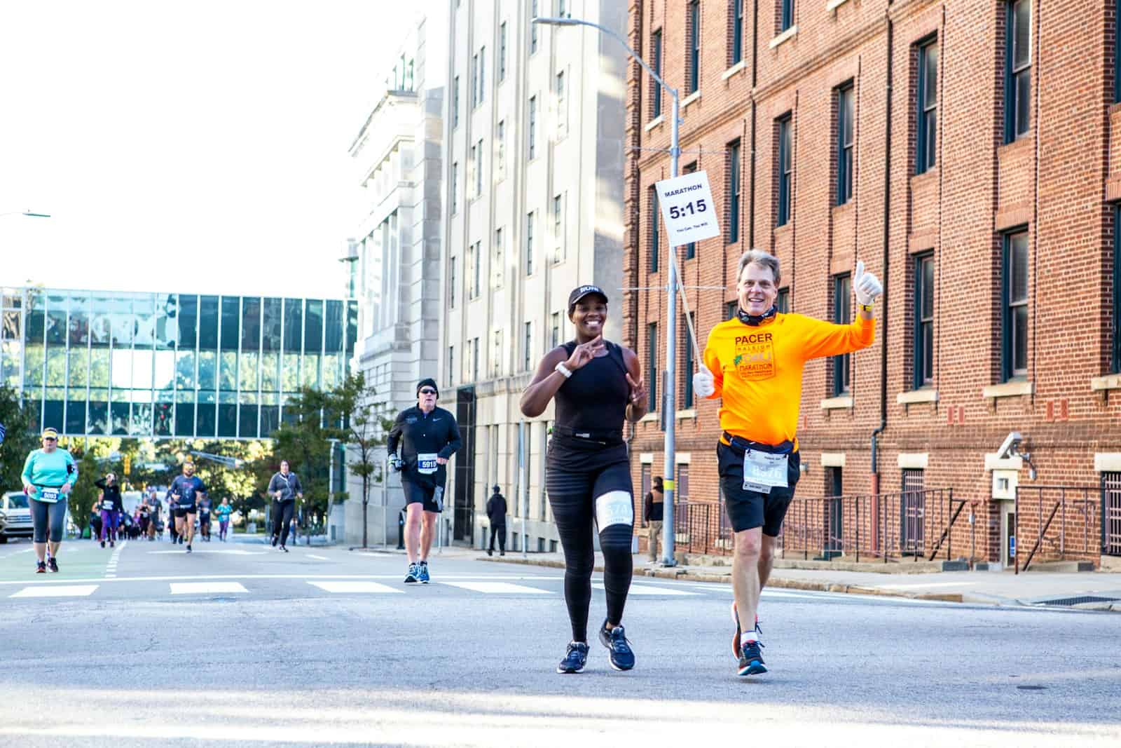 man in orange t-shirt and black shorts running on road during daytime